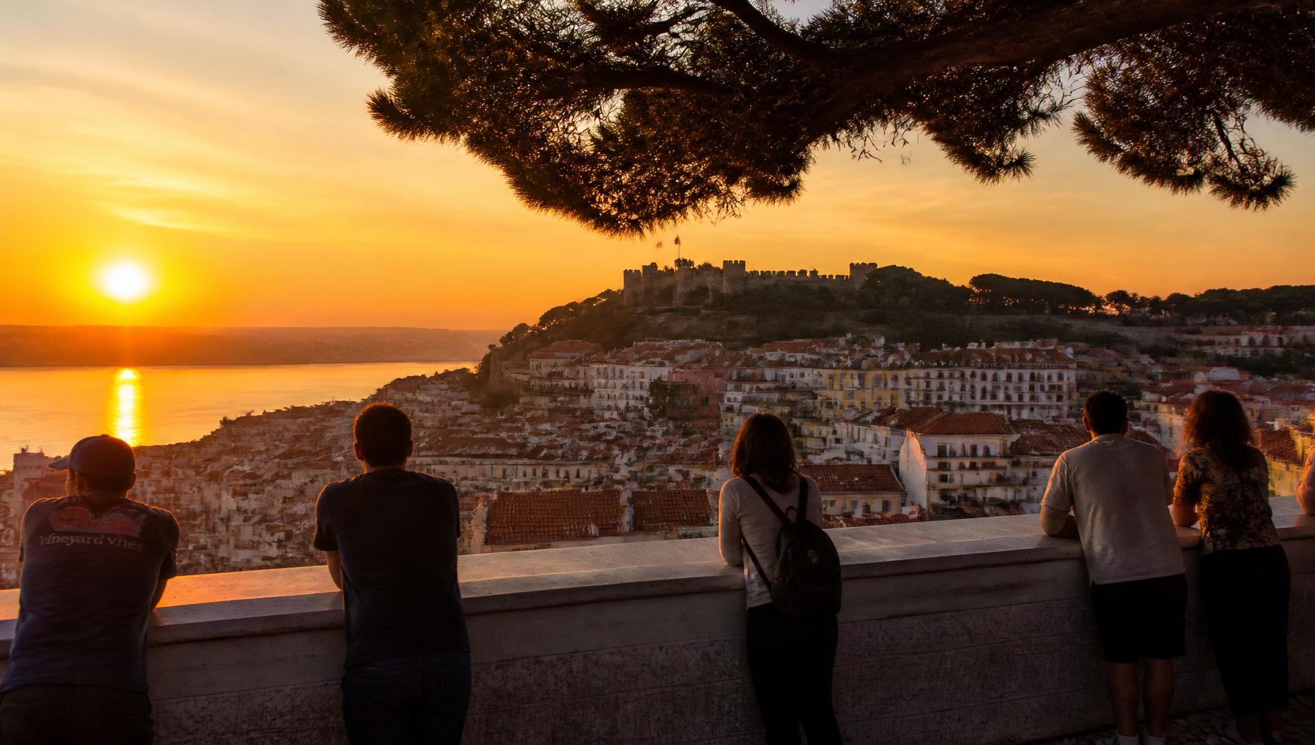 A guide walking with guests through Alfama at dusk